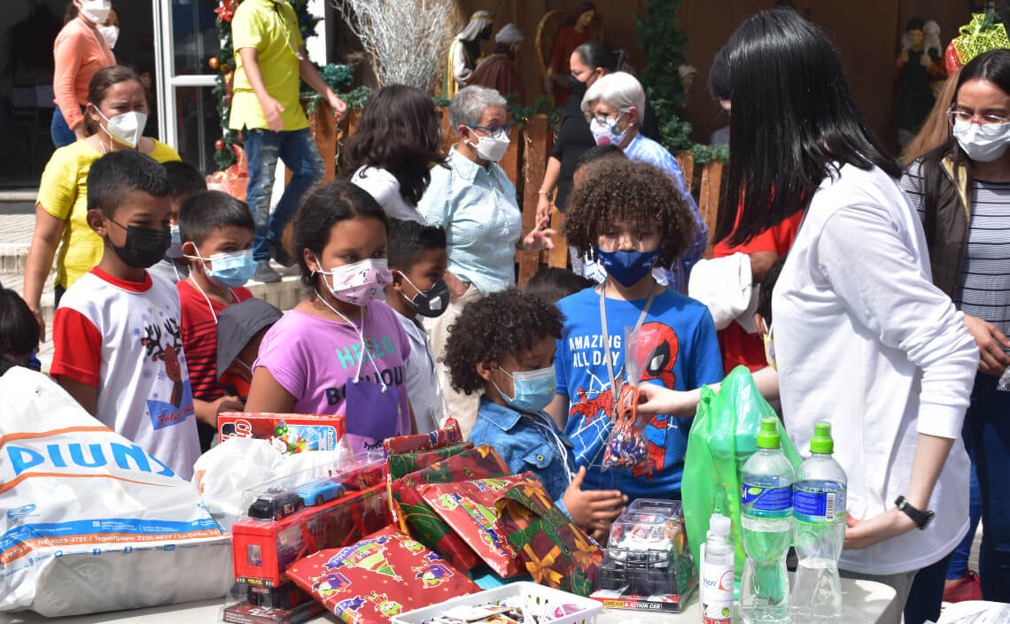 Niños recibiendo regalos en la posada navideña